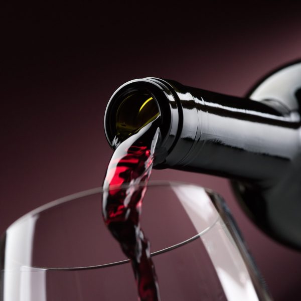 Pouring red wine from a bottle into a wineglass: wine tasting and celebration